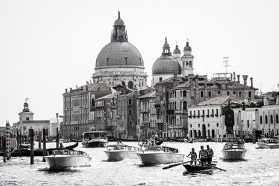 Boats in grand canal by santa maria della salute against sky on sunny day