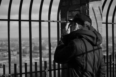 Man standing by railing against sky