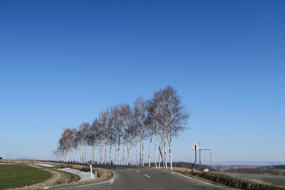 Country road against clear blue sky