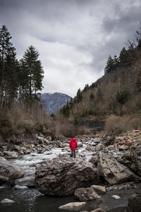 Man on rock by mountains against sky