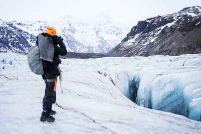 Rear view of man walking on snow covered mountain