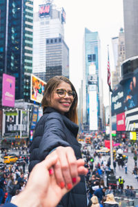 Portrait of happy woman against buildings in city