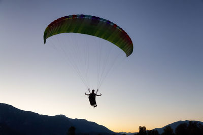 Silhouette person paragliding against sky