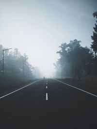 Empty road amidst trees against sky