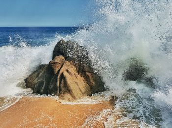 Waves splashing on sea against sky