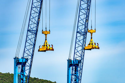 Low angle view of crane against blue sky