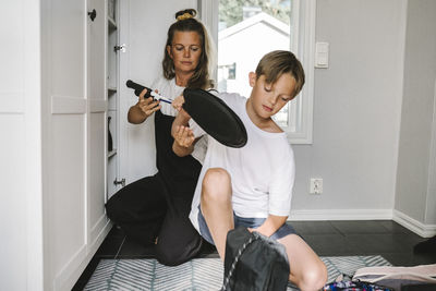 Mother and son holding badminton at home