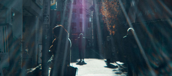 Rear view of people walking on street in city