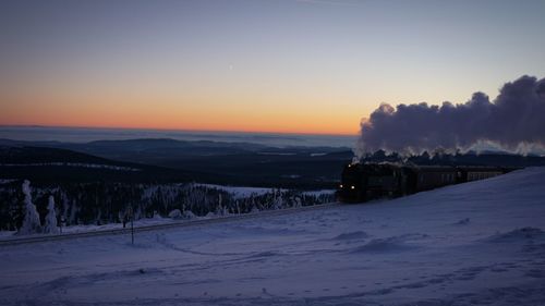 Scenic view of frozen landscape against sky during sunset