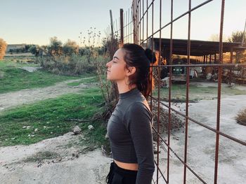 Young woman with eyes closed leaning on rusty metal structure