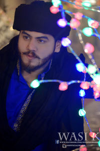 Close-up of man with illuminated lighting equipment in city at night