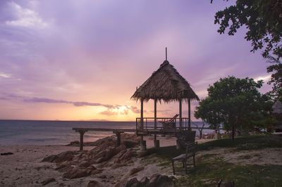 Built structure on beach against sky during sunset