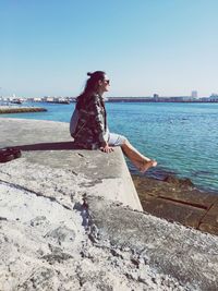 Portrait of woman standing by sea against clear sky