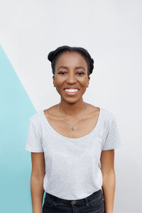 Portrait of young woman standing against white background