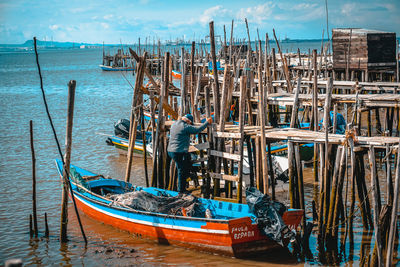 Fishing boats moored in sea against sky