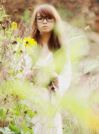 Portrait of woman standing by flowering plants