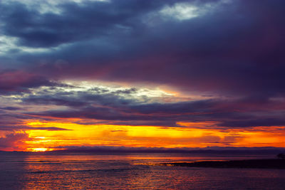 Scenic view of sea against dramatic sky during sunset