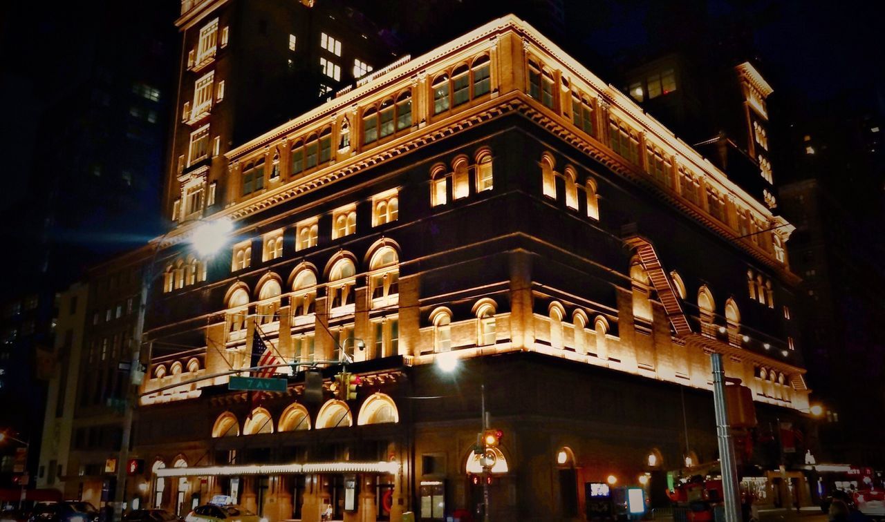 LOW ANGLE VIEW OF ILLUMINATED BUILDING IN CITY AT NIGHT