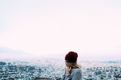 Rear view of woman looking at cityscape against clear sky
