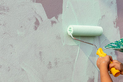 Close-up of hand holding painting against wall