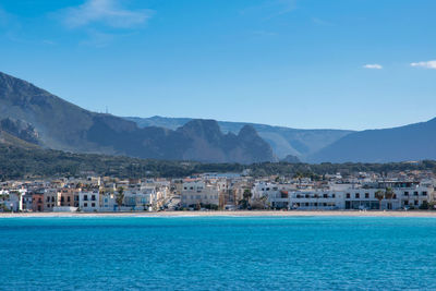 Sea by buildings against blue sky