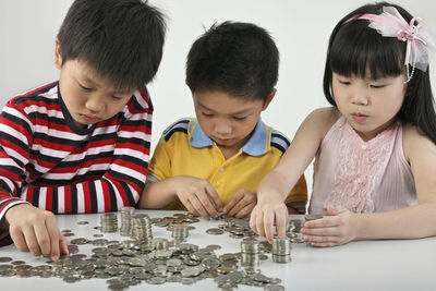 Children counting coins on table against white background