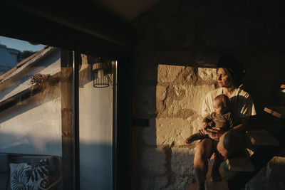 Mother with baby looking through window