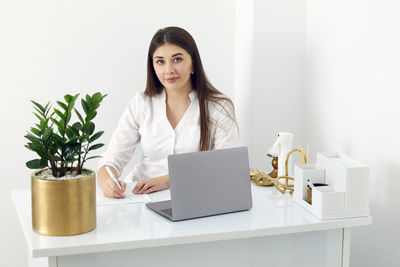 Portrait of young woman using laptop on table