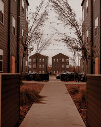 Empty footpath amidst buildings in city