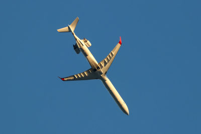 Low angle view of airplane against clear blue sky