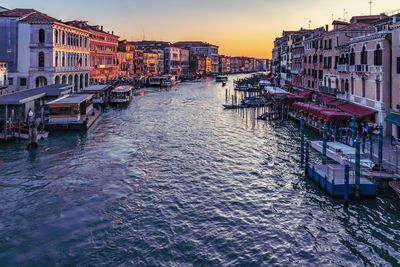 Canal amidst buildings against sky during sunset