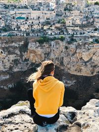 Rear view of woman sitting on rock