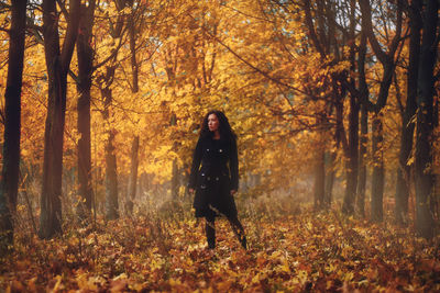 Full length of woman standing in forest during autumn 
