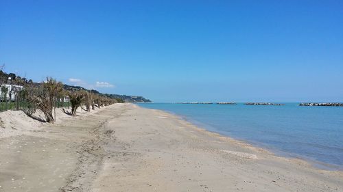 Scenic view of beach against clear blue sky