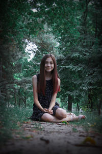 Portrait of young woman sitting in forest