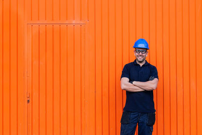 Portrait of man standing against orange wall