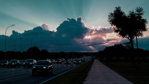 Cars on road against sky at sunset