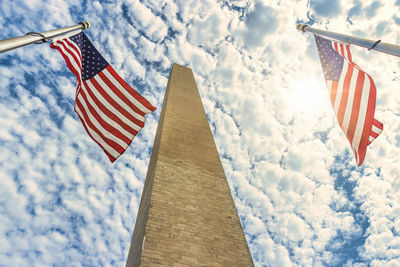 Low angle view of flag flags against cloudy sky