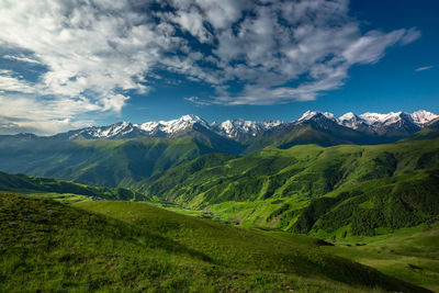 Beautiful green mountains covered with snow on the peaks