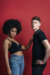 Stylish diverse girlfriend and boyfriend posing in a studio shooting with red background