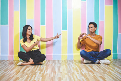 Young couple sitting on floor against wall