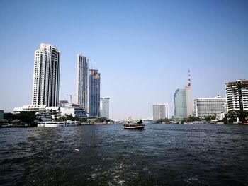 Cranes in city against clear sky