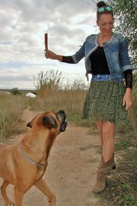 Woman playing with dog while standing on field