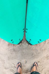 Low section of person with surfboards standing on beach