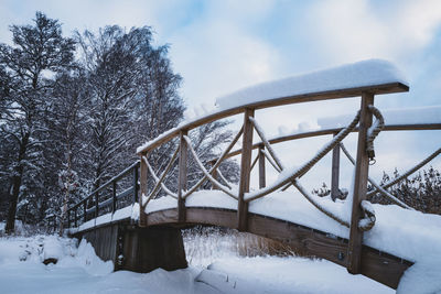 Snow covered footbridge  against sky