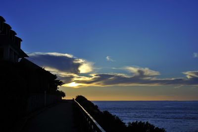 Scenic view of sea and silhouette buildings against sky during sunset