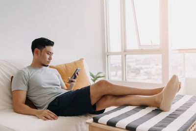 Young woman using laptop while sitting on bed at home