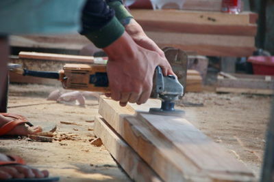 Low section of man working on wood in workshop