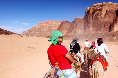 Portrait of smiling man riding camel at desert