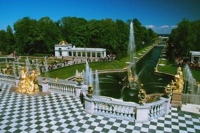 Fountain in swimming pool by trees against sky